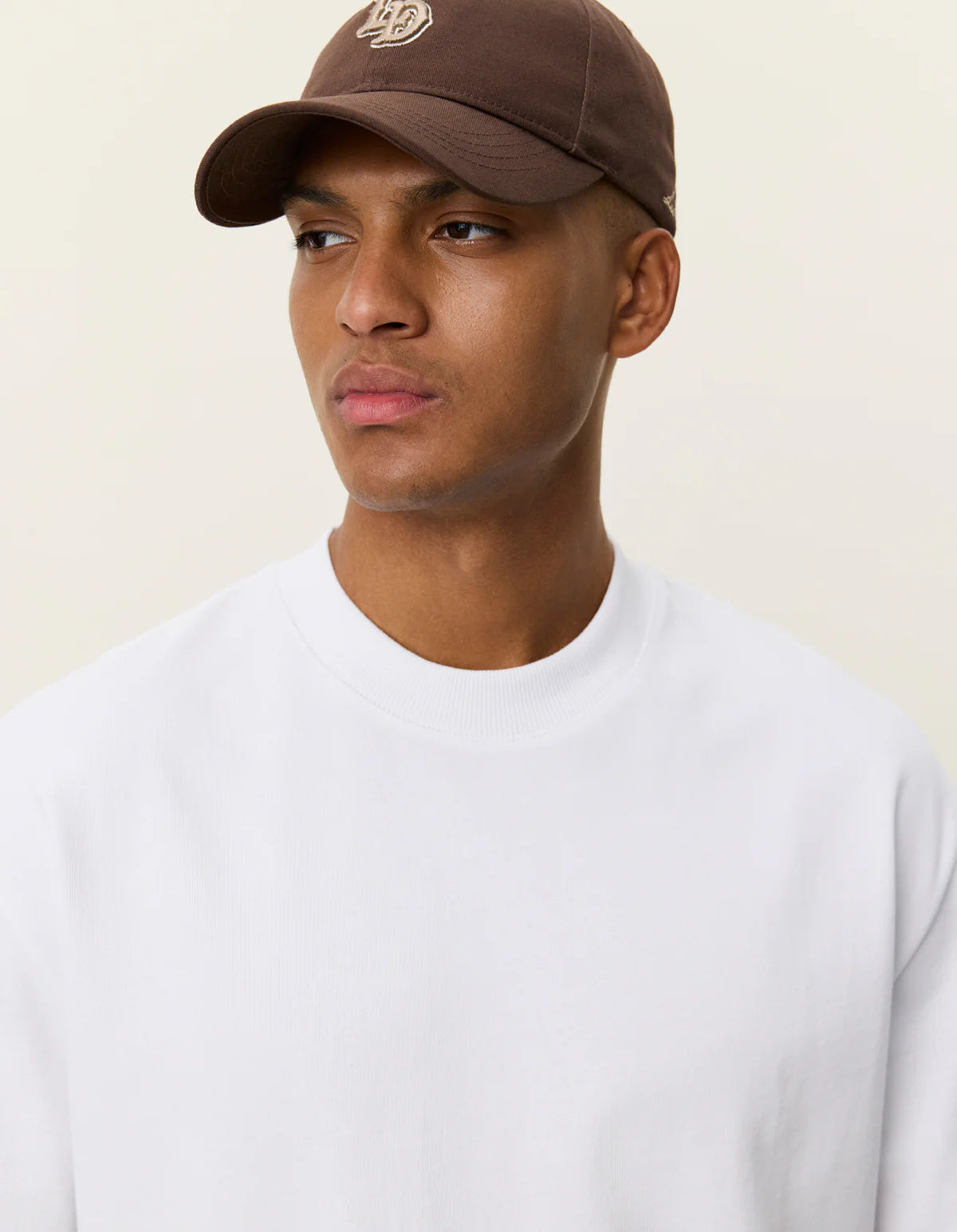 Nærbillede af model med kasket i Les Deux Carl T-shirt i hvid