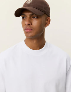 Nærbillede af model med kasket i Les Deux Carl T-shirt i hvid