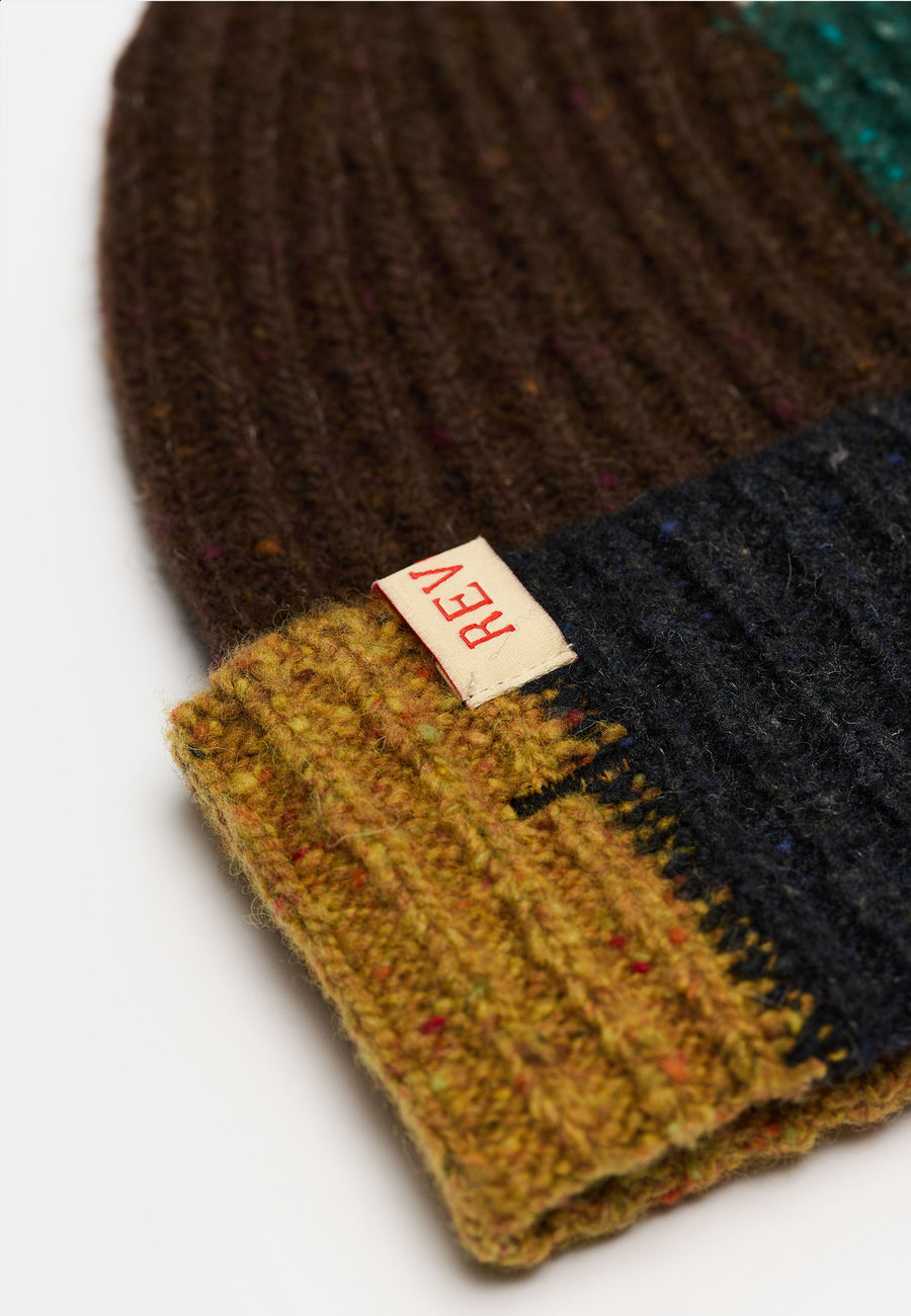 Nærbillede af rib-strik og læderlabel på Revolution Melange beanie 9329 i mørkegrøn med farveblokke i brun, sort og sennep