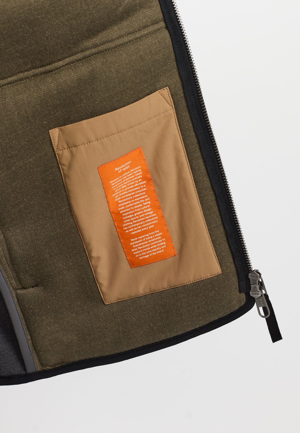 Detalje af orange label på Revolution Blocked teddy jakke 7028 i mørkegrå