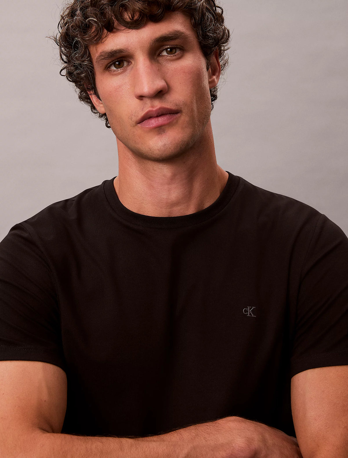 Nærbillede af model i sort Calvin Klein Stretch Slim Fit T-shirt med korslagte arme