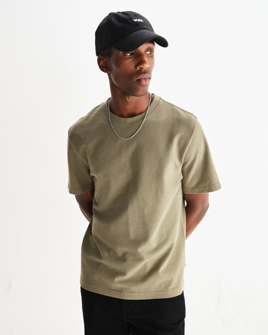 Model med kasket i Wax London Dean T-shirt med struktur i grøn