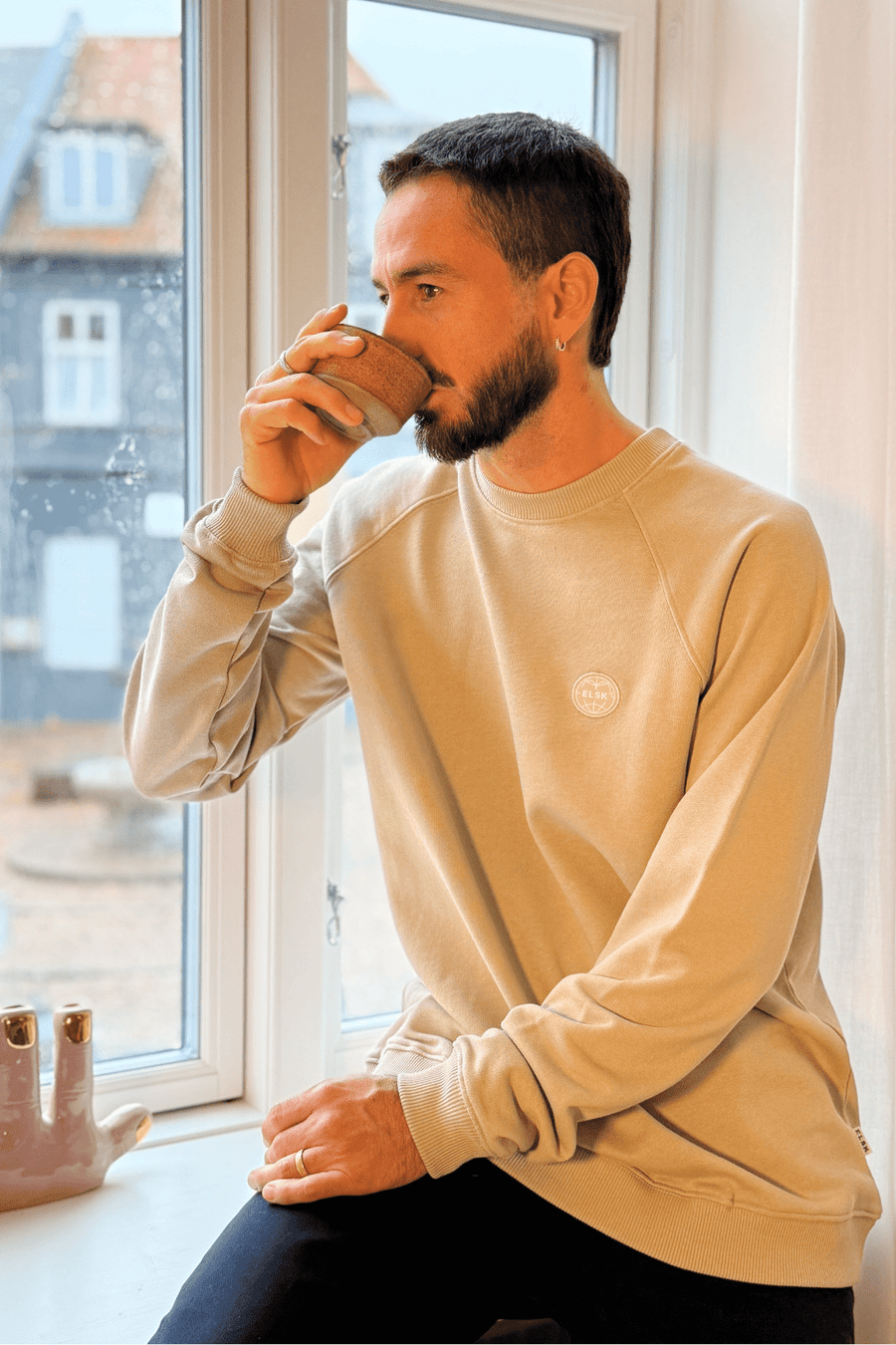 Siddende model i Elsk Globe raglan sweatshirt i Sand Stone beige set fra siden