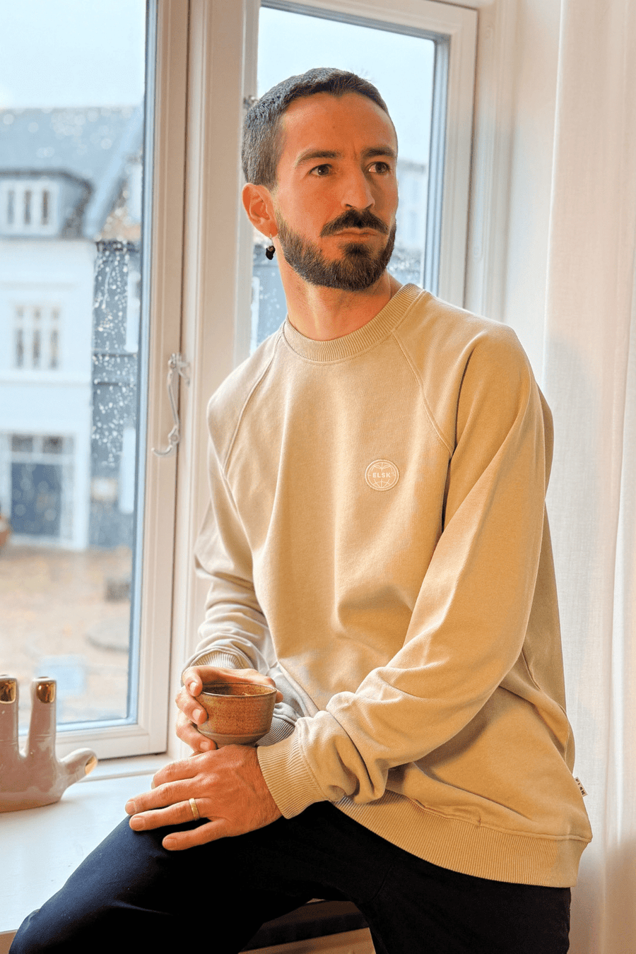 Siddende model i Elsk Globe raglan sweatshirt i Sand Stone beige