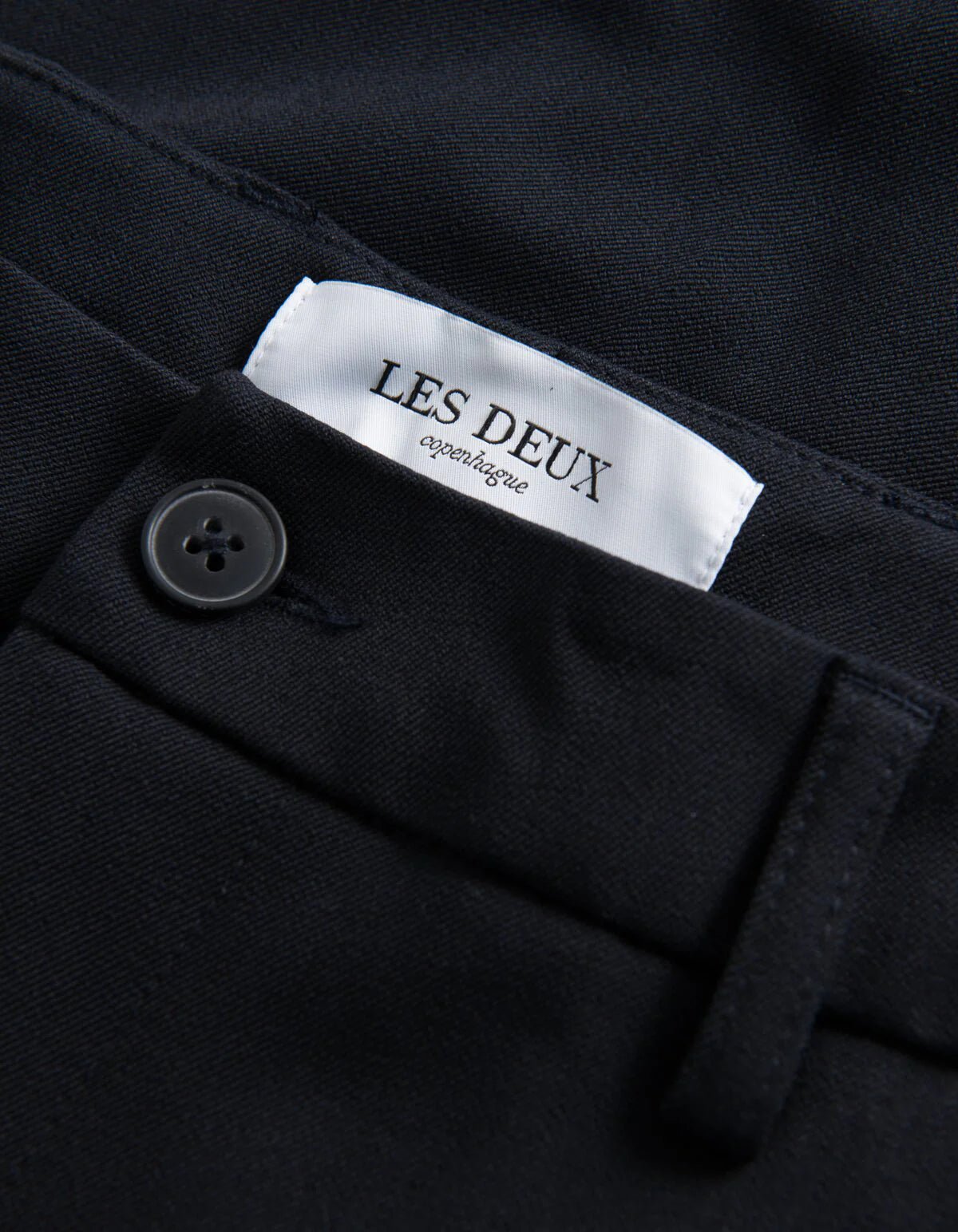 Detalje af label på Les Deux Como Regular habitbukser i Dark Navy