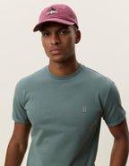 Nærbillede af model med kasket i Les Deux Core Seasonal T-shirt i Laurel Wreath Green