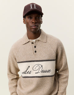 Nærbillede af model med kasket i Les Deux Signature melange strikpolo i Dark Sand melange med logostribe