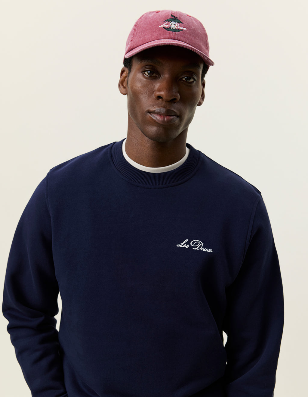 Nærbillede af model med kasket i Les Deux Signature print sweatshirt i Dark Navy