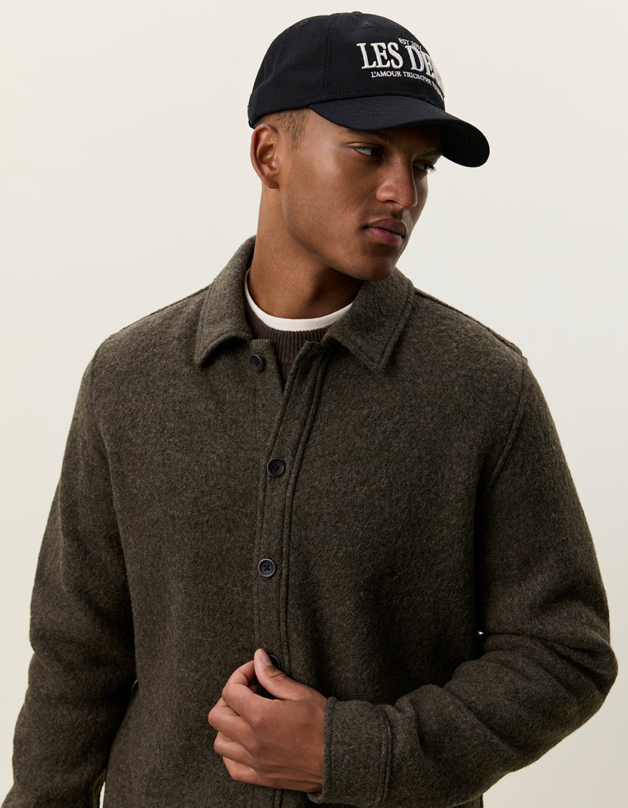 Nærbillede af model med kasket i Les Deux bouclé overshirt i uld i Duffel Bag grøn