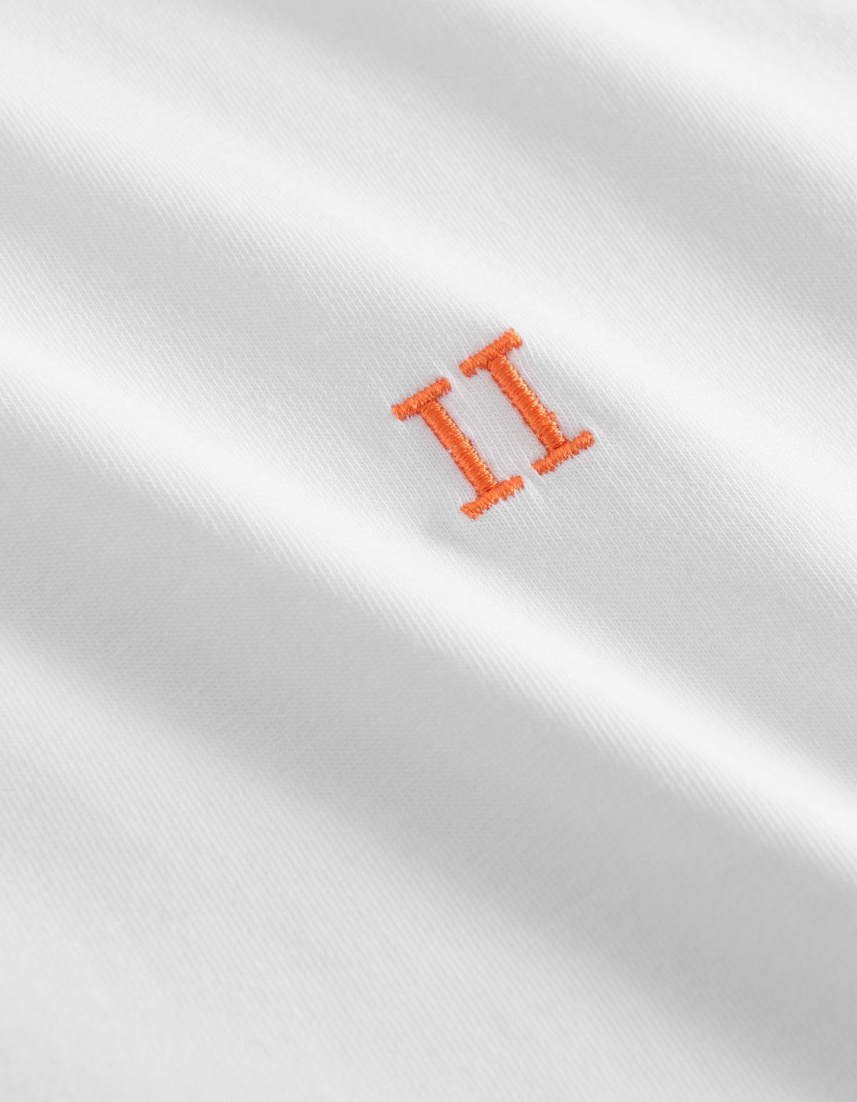 Detalje af orange broderet logo på Les Deux Nørregaard T-shirt i hvid