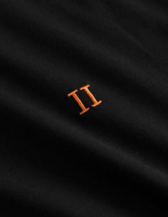 Detalje af orange broderet logo på Les Deux Nørregaard T-shirt i sort