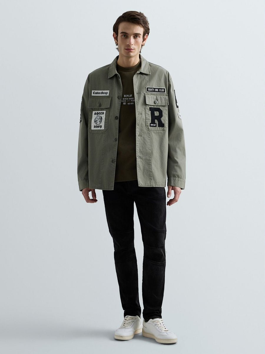 Replay overshirt med logo og patches i army grøn båret åben med sorte bukser – helfigur