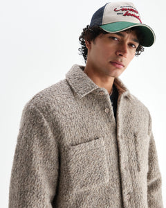 Model med kasket i Wax London Mount vendbar overshirt i bouclé-uld i natur